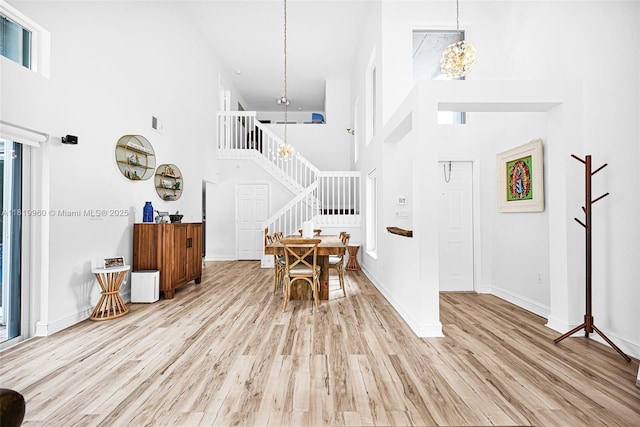 1151 W Lake St, Hollywood, FL 33019 - dining area featuring a high ceiling, stairs, a chandelier, light wood-type flooring, and plenty of natural light