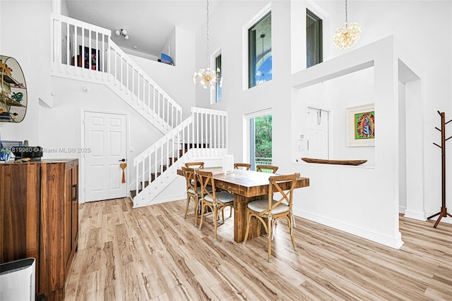 1151 W Lake St, Hollywood, FL 33019 - dining space with stairs, a chandelier, light wood finished floors, and a towering ceiling