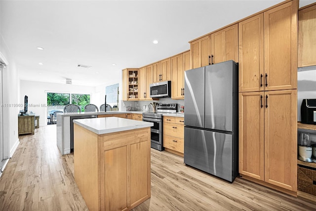 1151 W Lake St, Hollywood, FL 33019 - kitchen featuring stainless steel appliances, light wood-style flooring, a kitchen island, glass insert cabinets, and recessed lighting