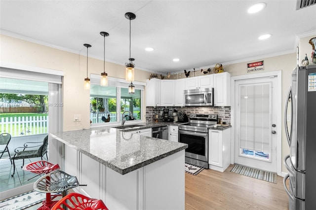 1360 S Audubon Dr, Homestead, FL 33035 - kitchen featuring stainless steel appliances, a peninsula, white cabinets, light wood-type flooring, and tasteful backsplash