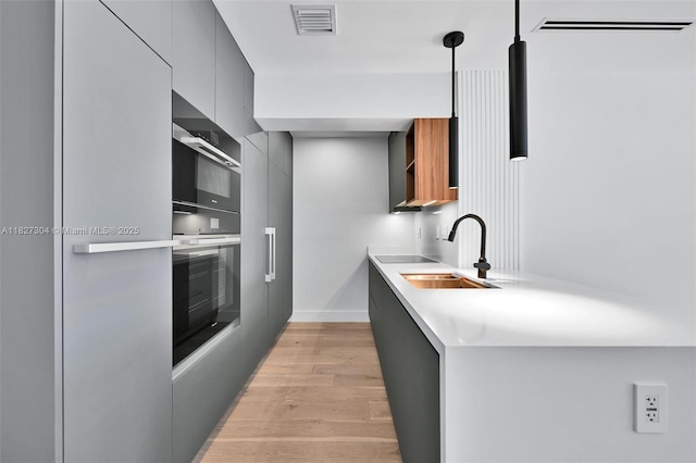 200 Sunrise Dr Unit 200C, Key Biscayne, FL 33149 - kitchen with modern cabinets, light wood-style flooring, light countertops, gray cabinetry, and hanging light fixtures