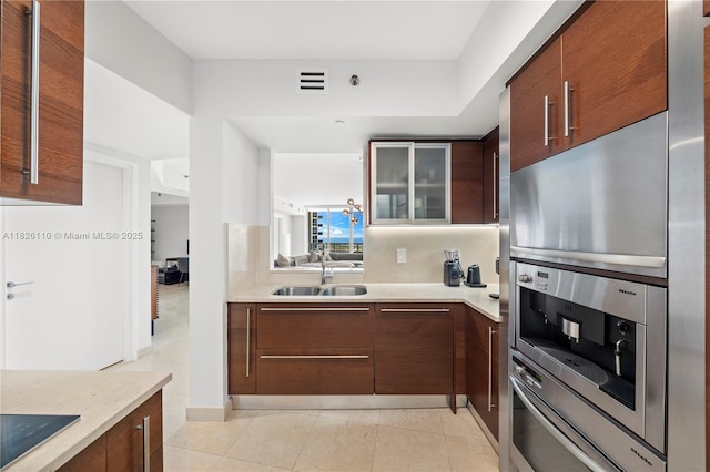 450 Alton Rd Unit 2705, Miami Beach, FL 33139 - kitchen featuring light countertops, glass insert cabinets, black electric cooktop, modern cabinets, and oven