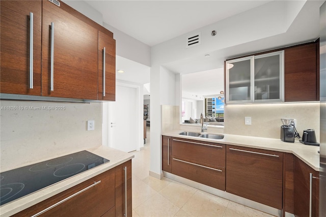 450 Alton Rd Unit 2705, Miami Beach, FL 33139 - kitchen with black electric cooktop, light countertops, glass insert cabinets, and modern cabinets
