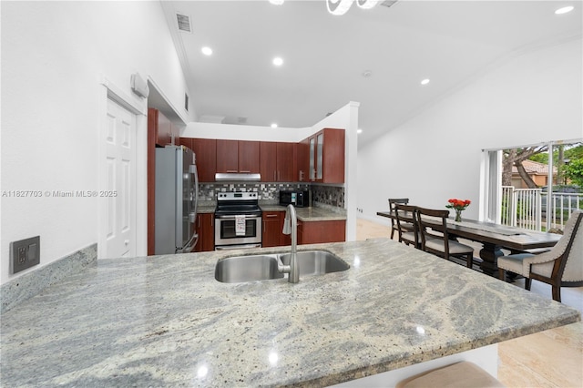 4361 Mahogany Ridge Dr, Weston, FL 33331 - kitchen featuring appliances with stainless steel finishes, vaulted ceiling, under cabinet range hood, reddish brown cabinets, and recessed lighting