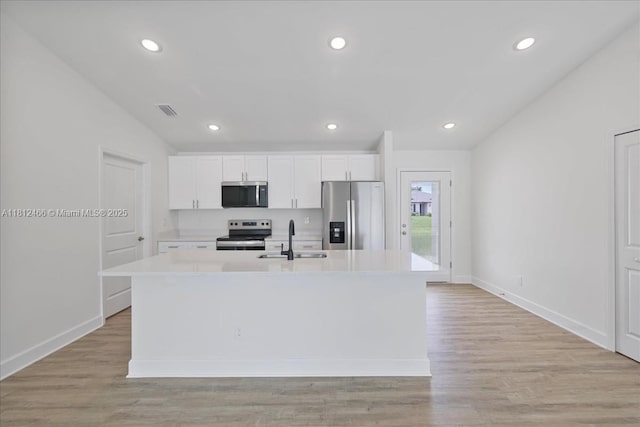 1119 NW 19th St, Cape Coral, FL 33993 - kitchen featuring appliances with stainless steel finishes, a kitchen island with sink, white cabinets, light countertops, and recessed lighting