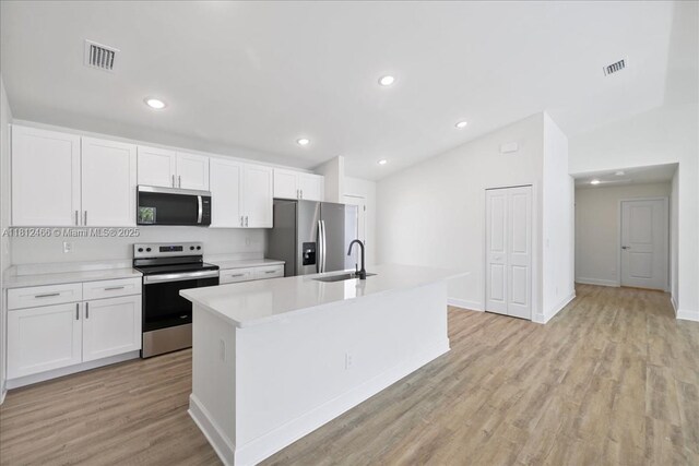 1119 NW 19th St, Cape Coral, FL 33993 - kitchen featuring appliances with stainless steel finishes, lofted ceiling, an island with sink, white cabinets, and light countertops