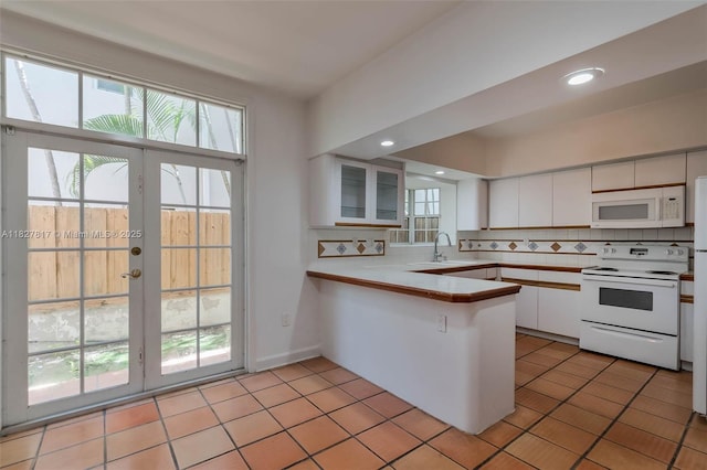 3136 Virginia St, Miami, FL 33133 - kitchen featuring white appliances, a peninsula, white cabinetry, tasteful backsplash, and light countertops