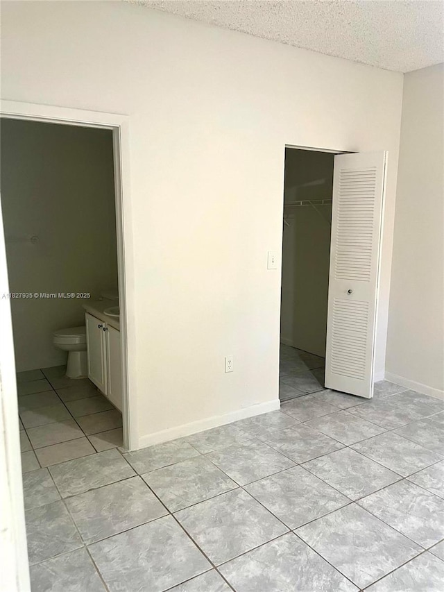 2331 NW 96th Ter Unit 17F, Pembroke Pines, FL 33024 - unfurnished bedroom featuring light tile patterned floors, a closet, a textured ceiling, and ensuite bath