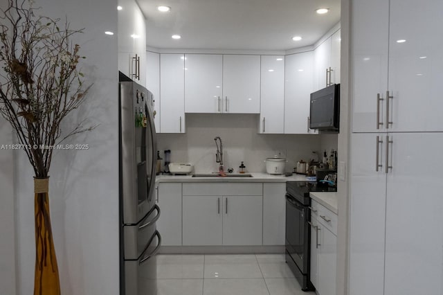 90 E 41st St, Hialeah, FL 33013 - kitchen featuring black appliances, white cabinets, light countertops, modern cabinets, and light tile patterned floors