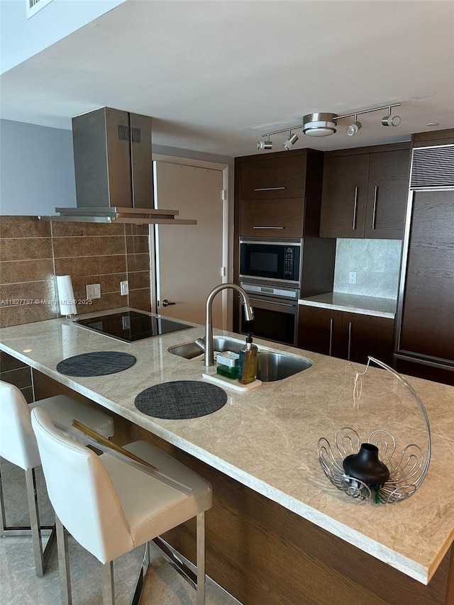 495 Brickell Ave Unit 5211, Miami, FL 33131 - kitchen with black appliances, backsplash, wall chimney range hood, dark brown cabinets, and a peninsula