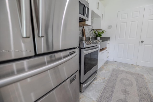 2125 SW 26th St, Miami, FL 33133 - kitchen with stainless steel appliances, white cabinetry, decorative backsplash, and light marble finish flooring