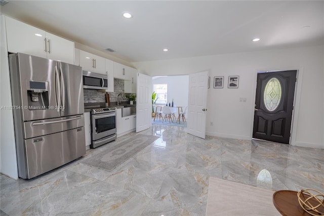 2125 SW 26th St, Miami, FL 33133 - kitchen with stainless steel appliances, white cabinets, backsplash, recessed lighting, and light marble finish flooring