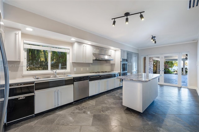 1375 N Biscayne Point Rd, Miami Beach, FL 33141 - kitchen with stainless steel dishwasher, under cabinet range hood, plenty of natural light, crown molding, and stone tile flooring