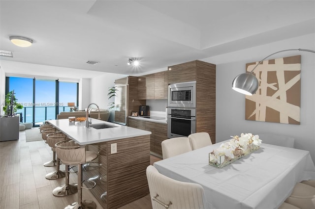 460 NE 28th St Unit 2407, Miami, FL 33137 - kitchen featuring stainless steel appliances, brown cabinets, a kitchen breakfast bar, light countertops, and expansive windows