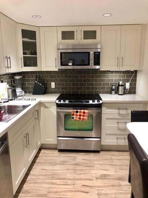 400 Kings Point Dr Unit 820, Sunny Isles Beach, FL 33160 - kitchen featuring appliances with stainless steel finishes, light countertops, light wood-type flooring, white cabinets, and recessed lighting