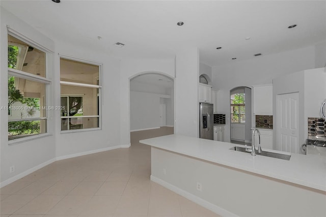 3843 Oak Ridge Cir, Weston, FL 33331 - kitchen with arched walkways, stainless steel fridge, tasteful backsplash, white cabinetry, and light countertops