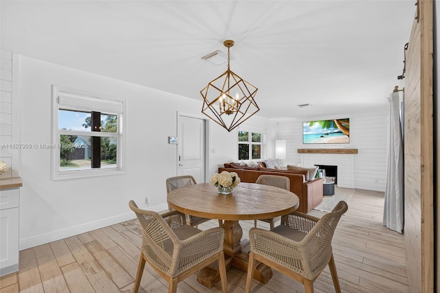 228 Rutland Blvd, West Palm Beach, FL 33405 - dining area featuring light wood-style floors, a fireplace, and a chandelier