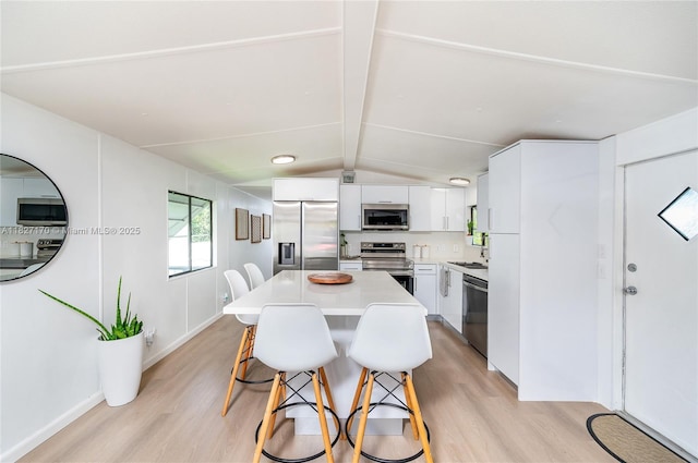 456 Bowie Ln, Key Largo, FL 33037 - kitchen featuring stainless steel appliances, light wood-style floors, a breakfast bar area, and white cabinets