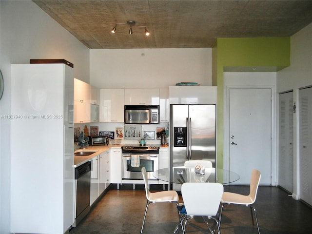133 NE 2nd Ave Unit 815, Miami, FL 33132 - kitchen with stainless steel appliances, white cabinetry, light countertops, finished concrete flooring, and a high ceiling