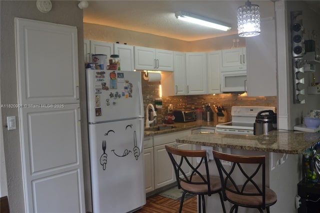 56 Norwich C Unit 56, West Palm Beach, FL 33417 - kitchen with white appliances, white cabinetry, backsplash, and a peninsula