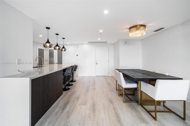3400 SW 27th Ave Unit 1605, Miami, FL 33133 - kitchen featuring light wood finished floors, recessed lighting, light countertops, a kitchen island with sink, and decorative light fixtures