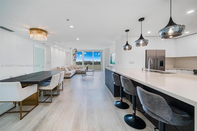 3400 SW 27th Ave Unit 1605, Miami, FL 33133 - kitchen with modern cabinets, white cabinets, stainless steel refrigerator with ice dispenser, light wood finished floors, and light countertops
