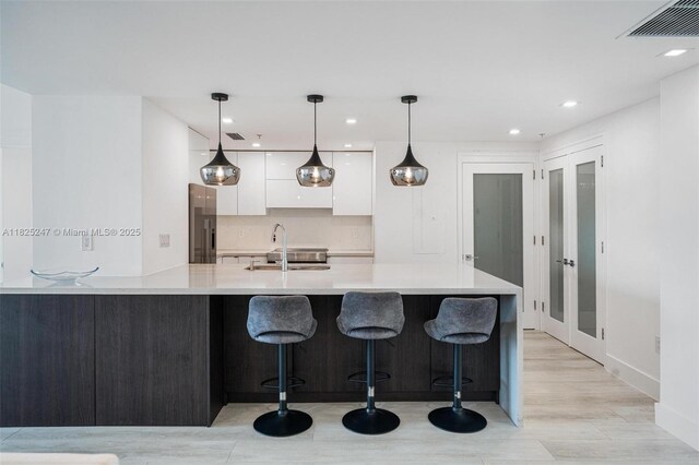 3400 SW 27th Ave Unit 1605, Miami, FL 33133 - kitchen featuring modern cabinets, white cabinetry, light countertops, recessed lighting, and a kitchen breakfast bar