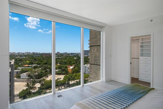 3400 SW 27th Ave Unit 1605, Miami, FL 33133 - bedroom featuring a city view, wood finished floors, multiple windows, a walk in closet, and a wall of windows