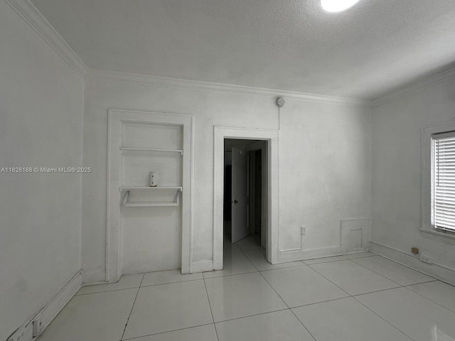 126 Mendoza Ave Unit 1, Coral Gables, FL 33134 - unfurnished bedroom featuring crown molding, a closet, a textured ceiling, and light tile patterned floors