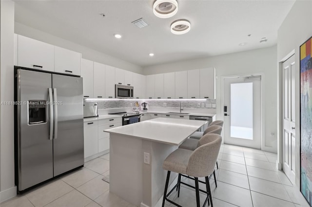 8001 NW 41st St Unit F-112, Doral, FL 33166 - kitchen featuring stainless steel appliances, a kitchen breakfast bar, a kitchen island, white cabinetry, and recessed lighting