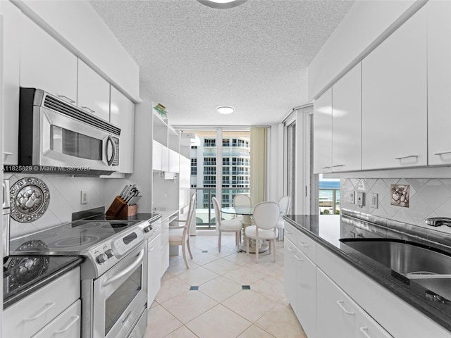 16445 Collins Ave Unit 726, Sunny Isles Beach, FL 33160 - kitchen featuring appliances with stainless steel finishes, a textured ceiling, backsplash, white cabinets, and light tile patterned flooring