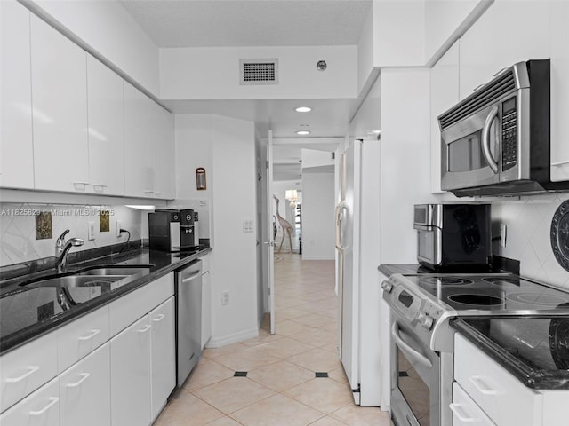 16445 Collins Ave Unit 726, Sunny Isles Beach, FL 33160 - kitchen featuring stainless steel appliances, white cabinetry, decorative backsplash, dark stone countertops, and light tile patterned floors