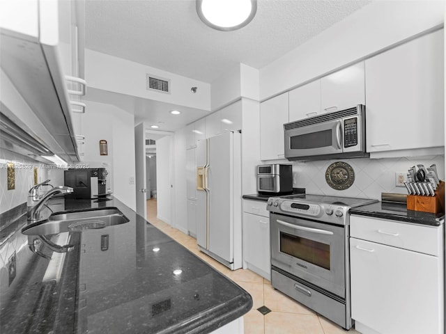 16445 Collins Ave Unit 726, Sunny Isles Beach, FL 33160 - kitchen with stainless steel appliances, white cabinetry, decorative backsplash, a textured ceiling, and dark stone countertops