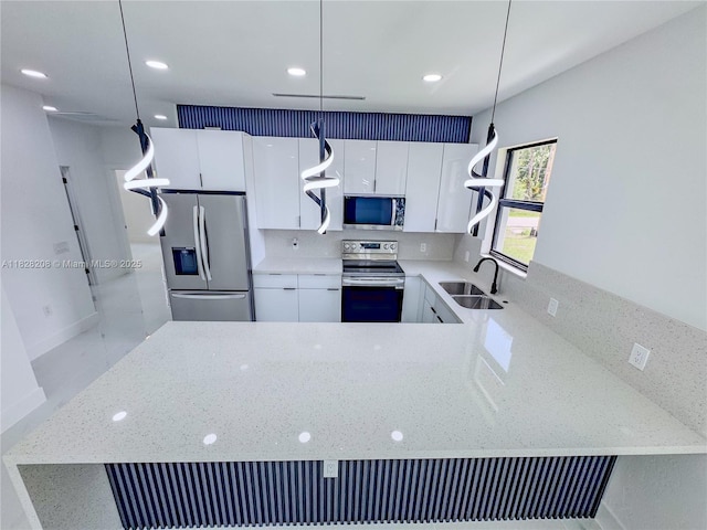 505 W 10th St, Lehigh Acres, FL 33972 - kitchen featuring stainless steel appliances, light stone countertops, pendant lighting, a peninsula, and white cabinetry