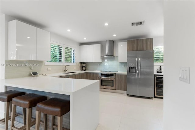 2180 Alamanda Dr, North Miami, FL 33181 - kitchen featuring stainless steel appliances, wall chimney exhaust hood, wine cooler, modern cabinets, and a kitchen breakfast bar