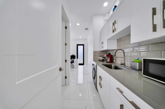 1550 SW 89th Ct, Miami, FL 33174 - kitchen with black microwave, tasteful backsplash, light marble finish floors, washer / clothes dryer, and white cabinets