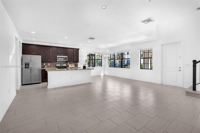11735 SW 13th Ct, Pembroke Pines, FL 33025 - kitchen featuring appliances with stainless steel finishes, open floor plan, dark brown cabinets, tasteful backsplash, and a center island with sink