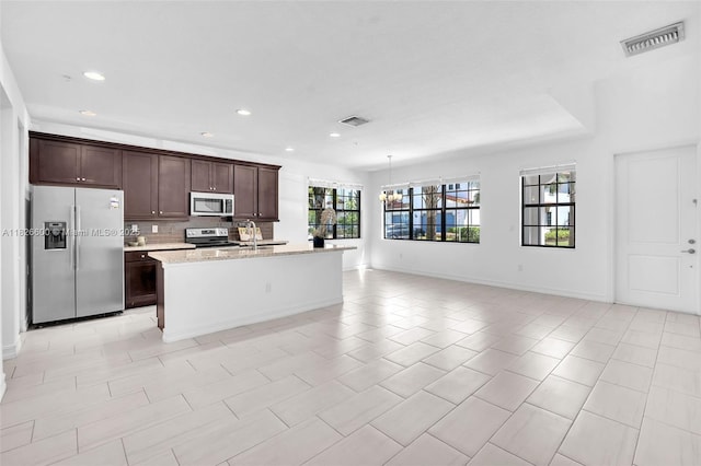 11735 SW 13th Ct, Pembroke Pines, FL 33025 - kitchen featuring appliances with stainless steel finishes, dark brown cabinetry, recessed lighting, an island with sink, and decorative backsplash