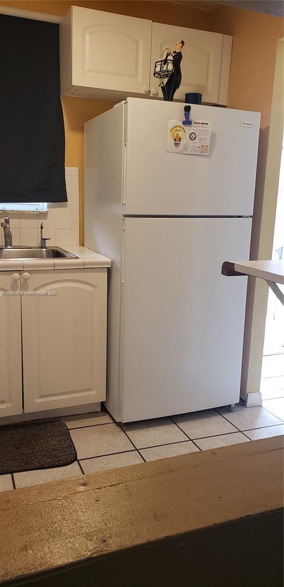 8280 Sunrise Lakes Blvd Unit 105, Sunrise, FL 33322 - kitchen featuring freestanding refrigerator, white cabinetry, light countertops, and light tile patterned floors