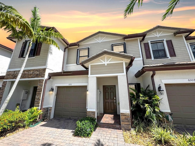 6011 W Paso Fino Pl, Davie, FL 33314 - view of property with stone siding, an attached garage, stucco siding, and decorative driveway