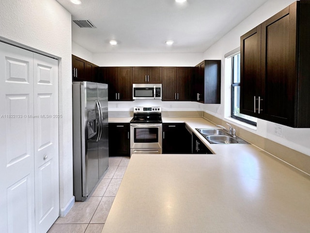 6011 W Paso Fino Pl, Davie, FL 33314 - kitchen featuring appliances with stainless steel finishes, light tile patterned flooring, dark brown cabinetry, light countertops, and a peninsula