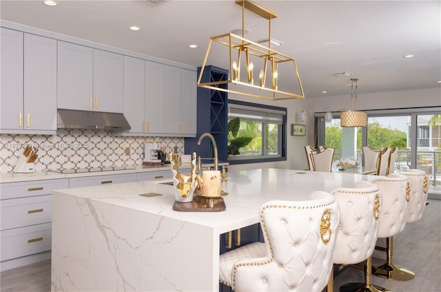 475 Bahia Honda Rd, Key Largo, FL 33037 - kitchen with under cabinet range hood, a center island with sink, backsplash, light wood-style floors, and recessed lighting