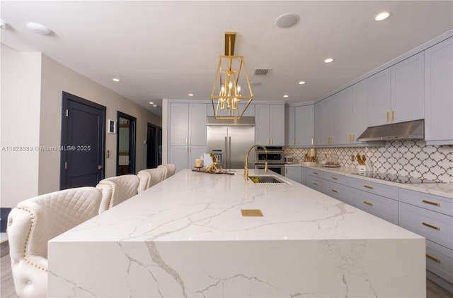 475 Bahia Honda Rd, Key Largo, FL 33037 - kitchen with under cabinet range hood, appliances with stainless steel finishes, a large island, backsplash, and recessed lighting