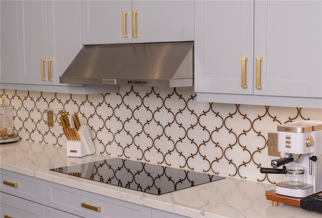 475 Bahia Honda Rd, Key Largo, FL 33037 - kitchen view of exhaust hood, decorative backsplash, black electric stovetop, light stone counters, and white cabinetry