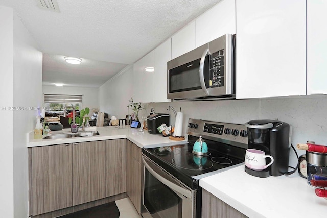 9917 W Okeechobee Rd Unit 3-303, Hialeah Gardens, FL 33016 - kitchen featuring stainless steel appliances, modern cabinets, light countertops, white cabinets, and a textured ceiling