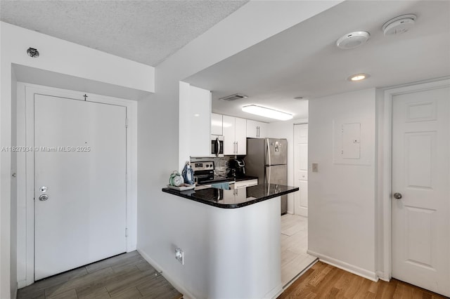770 Claughton Island Dr Unit 1210, Miami, FL 33131 - kitchen featuring stainless steel appliances, white cabinetry, wood finished floors, a peninsula, and dark countertops