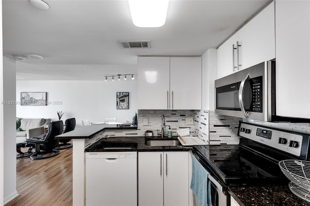 770 Claughton Island Dr Unit 1210, Miami, FL 33131 - kitchen with stainless steel appliances, a peninsula, white cabinetry, tasteful backsplash, and light wood-style flooring