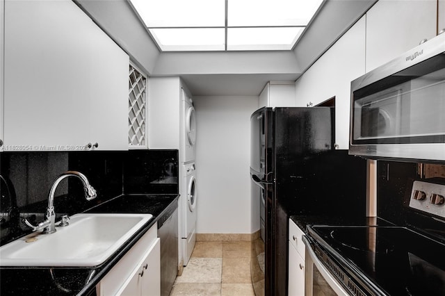 520 Brickell Key Dr Unit A1817, Miami, FL 33131 - kitchen with stacked washing machine and dryer, appliances with stainless steel finishes, white cabinetry, dark countertops, and light stone finish flooring