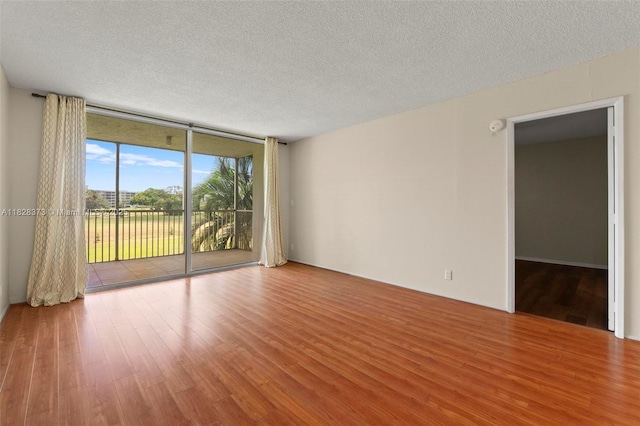 2851 S Palm Aire Dr Unit 205, Pompano Beach, FL 33069 - spare room featuring wood finished floors, floor to ceiling windows, a textured ceiling, and a smoke detector