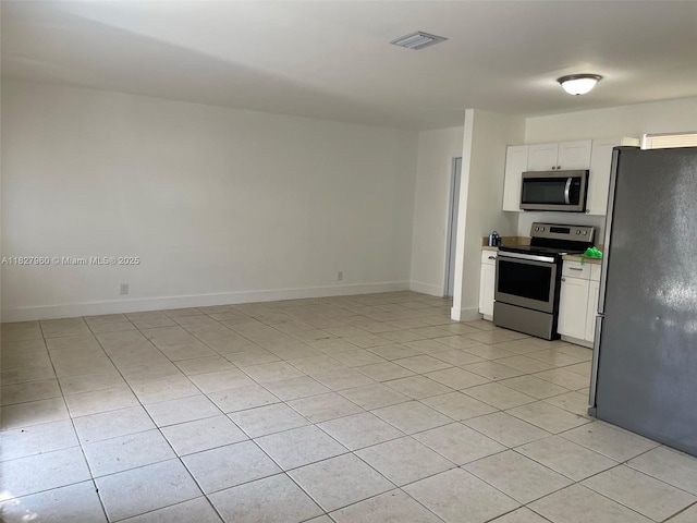 1842 Madison St, Hollywood, FL 33020 - kitchen with stainless steel appliances, light tile patterned flooring, white cabinetry, and light countertops